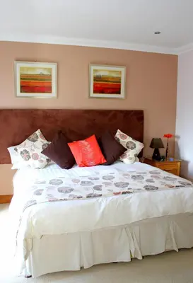 a bedroom with a large bed with red pillows at Backbrae House B&B in Lanark