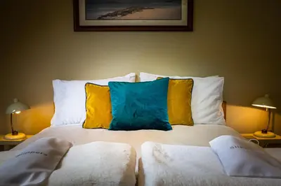 a bed with two pillows on it with two lamps at Cruickshanks Boutique B&B in Whiting Bay