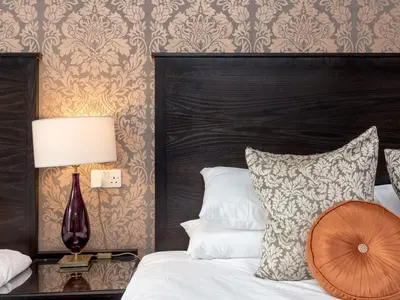 a bedroom with a bed with a black headboard and a lamp at Kirkstyle Hotel in Biggar