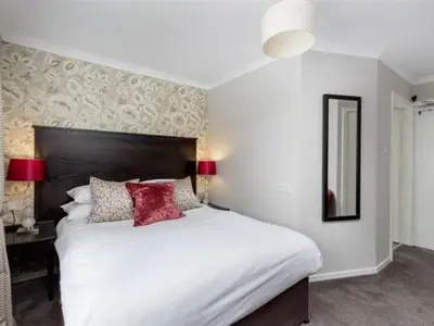 a bedroom with a large white bed with red pillows at Kirkstyle Hotel in Biggar