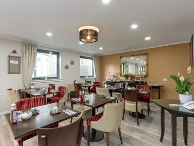 a restaurant with wooden tables and chairs and a mirror at Kirkstyle Hotel in Biggar