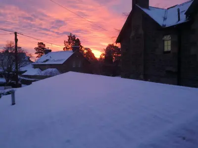 a snow covered yard with a sunset in the background at Lubnaig Guest House in Callander