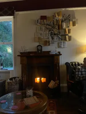 a man sitting in a chair in a living room with a fireplace at Creag Mhor Lodge in Onich