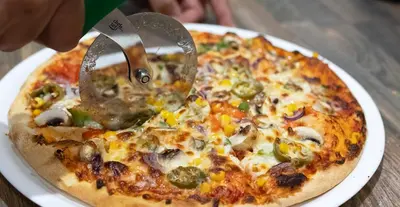 a pizza being cut with a pizza cutter at The County Hotel in Helensburgh