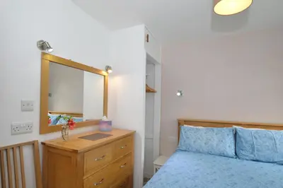 a bedroom with a bed and a dresser with a mirror at Larch Cottage in Blairmore
