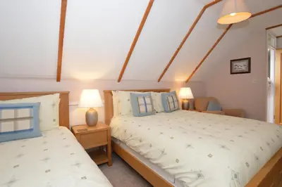 two beds in a bedroom with two lamps on tables at Larch Cottage in Blairmore