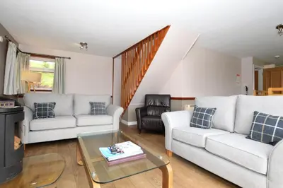 a living room with two couches and a table at Larch Cottage in Blairmore