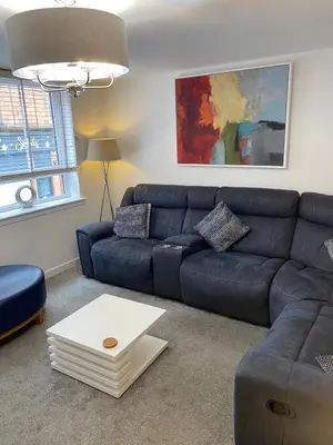 a living room with a blue couch and a table at Mossie Apartment in Ayr