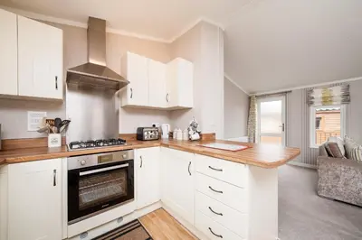 a kitchen with white cabinets and a stove top oven at Thistle Lodge in Auchterarder