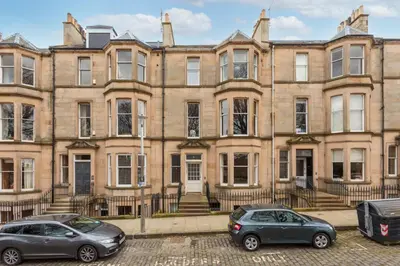 two cars parked in front of a large building at South Learmonth Gardens Apartment in Edinburgh