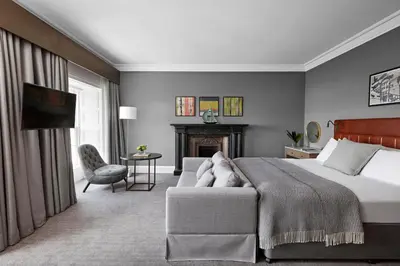 a bedroom with a bed and a couch and a fireplace at Kimpton Blythswood Square Hotel & Spa by IHG in Glasgow