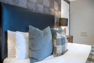 a bedroom with a bed with pillows and a blue headboard at The Allan Park in Stirling