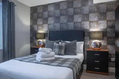 a bedroom with a bed with two lamps and towels on it at The Allan Park in Stirling