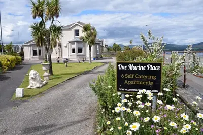 a sign in front of a house with flowers at One Marine Place in Port Bannatyne