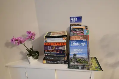 a shelf filled with books and a vase with flowers at Slateford House Apartment Ground Floor Main Door in Edinburgh