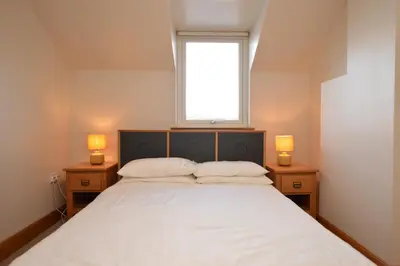 a bedroom with a large white bed with two lamps at Taigh na Mara in Kames