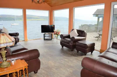 a living room with leather furniture and a view of the water at Taigh na Mara in Kames