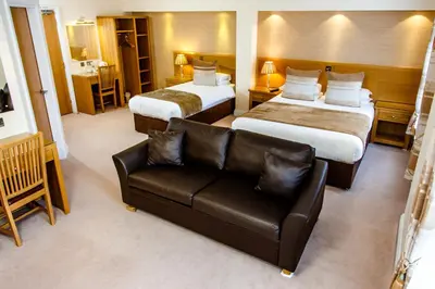 a hotel room with two beds and a couch at Adamson Hotel in Dunfermline