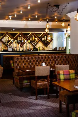 a restaurant with a bar and tables and chairs at Adamson Hotel in Dunfermline