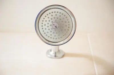 a silver shower head in a white tiled bathroom at Adamson Hotel in Dunfermline