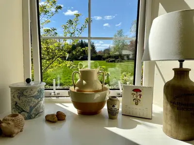 a table with a vase and a lamp and a window at Carnell Country Estate & Holiday Cottages in Ayrshire in Hurlford