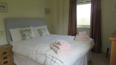 a bedroom with pink towels on a white bed at Aird Farm Holiday Cottages in Ardfern