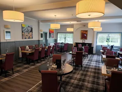 a dining room with tables and chairs and lights at Rob Roy Hotel in Aberfoyle