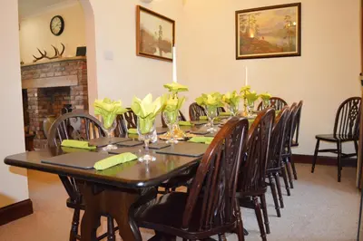 a dining room table with chairs and flowers on it at Culzean House in Ardentinny
