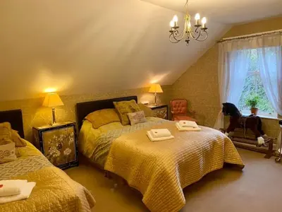 a bedroom with two beds and a chandelier at Rosebank House Bed & Breakfast in Strathyre