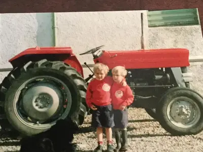 two young boys standing next to a red tractor at Oban Seil Farm The Bothy in Clachan