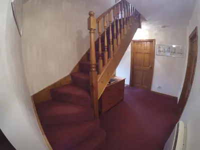 a wooden staircase with red carpet and a wooden door at Garbhein Bed & Breakfast in Kilmelford