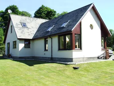a small white house with a black roof at Garbhein Bed & Breakfast in Kilmelford