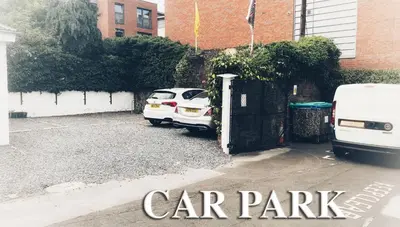 a white car parked in a parking lot next to a building at Averon Guest House in Edinburgh