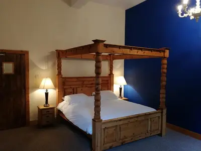a bedroom with a wooden canopy bed with two lamps at Broomhall Castle Hotel in Stirling