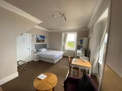 a small room with a bed and a table and a desk at The Bowmore House Bed and Breakfast in Bowmore
