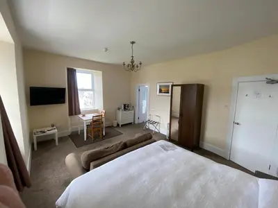 a bedroom with a bed and a couch and a tv at The Bowmore House Bed and Breakfast in Bowmore