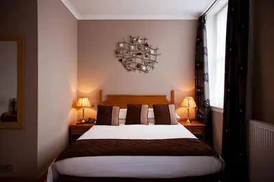 a bedroom with a bed with two lamps and two tables at The City Hotel in Dunfermline