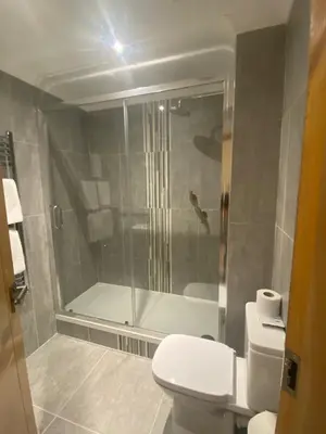 a bathroom with a shower and a toilet and a tub at The City Hotel in Dunfermline