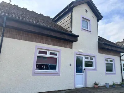 a white house with a window with a dog in it at Cunninghame 1 in Beith