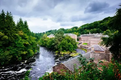 a river flowing through a town with trees at New Lanark Mill Hotel in Lanark