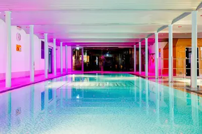 a swimming pool in a building with pink lighting at New Lanark Mill Hotel in Lanark