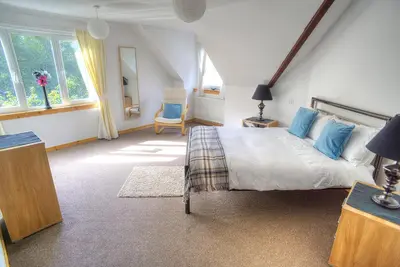 a bedroom with a large bed with blue pillows at ArdFyne on Lochfyne in Strachur