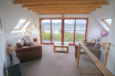 a living room with couches and a table and windows at ArdFyne on Lochfyne in Strachur
