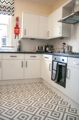 a kitchen with white cabinets and a patterned floor at Lexington Apartments in Rothesay
