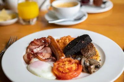 a plate of breakfast food on a table with a cup of coffee at Trigony Hotel and Garden Spa in Closeburn