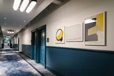 a hallway with blue doors and paintings on the wall at voco Grand Central Glasgow by IHG in Glasgow