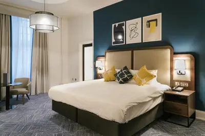 a hotel room with a large bed and a table at voco Grand Central Glasgow by IHG in Glasgow