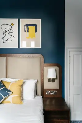 a bedroom with blue walls and a bed with a headboard at voco Grand Central Glasgow by IHG in Glasgow