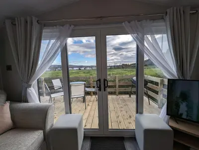 a living room with a sliding glass door to a deck at The Manor Sea View 8 in Dunoon