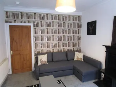 a living room with a couch and a wall of books at Westend Glasgow Apartment in Glasgow